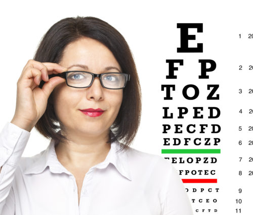 Woman with glasses standing next to an eye chart